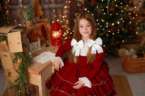 Portret dziewczynki w czerwonej sukience wśród świątecznych lampek