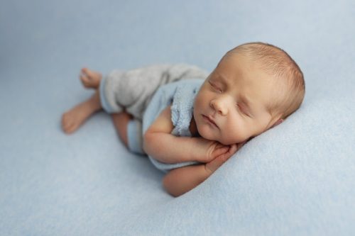 Noworodek leżący na boku – sesja noworodkowa studio Wyszków