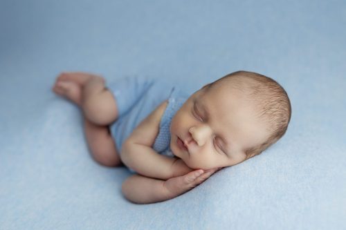 Noworodek leżący na boku – sesja noworodkowa studio Wyszków