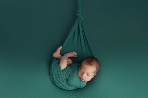 Noworodek otulony zielonym kokonem – sesja noworodkowa Wyszków