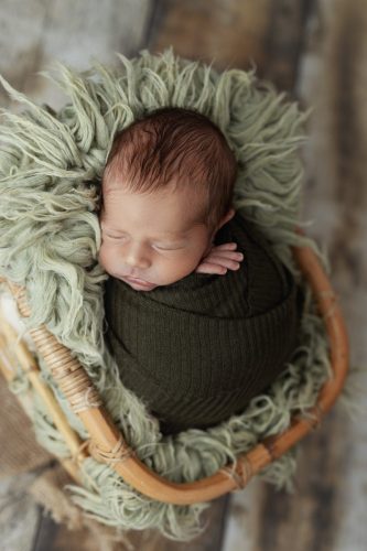 Noworodek otulony zielonym kokonem – sesja noworodkowa Wyszków