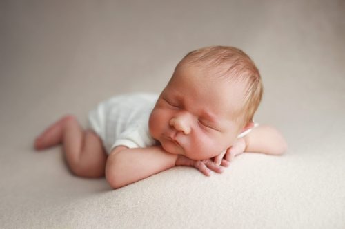 Noworodek leżący na brzuszku – sesja noworodkowa studio Wyszków
