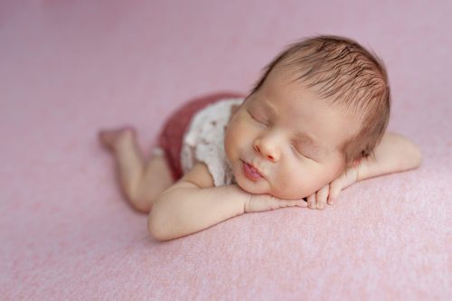 Noworodek leżący na brzuszku – sesja noworodkowa studio Wyszków