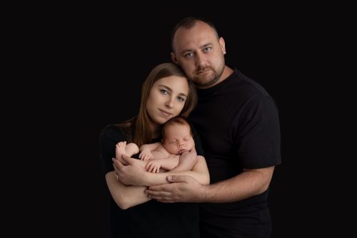 Rodzice przytulający noworodka – sesja noworodkowa w studio Wyszków