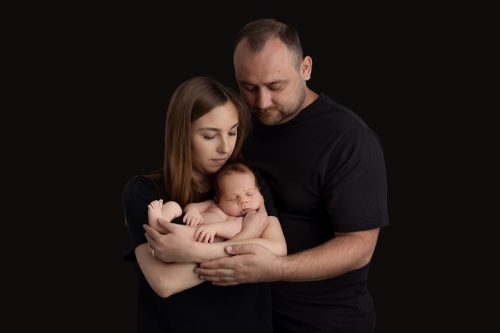Rodzice przytulający noworodka – sesja noworodkowa w studio Wyszków